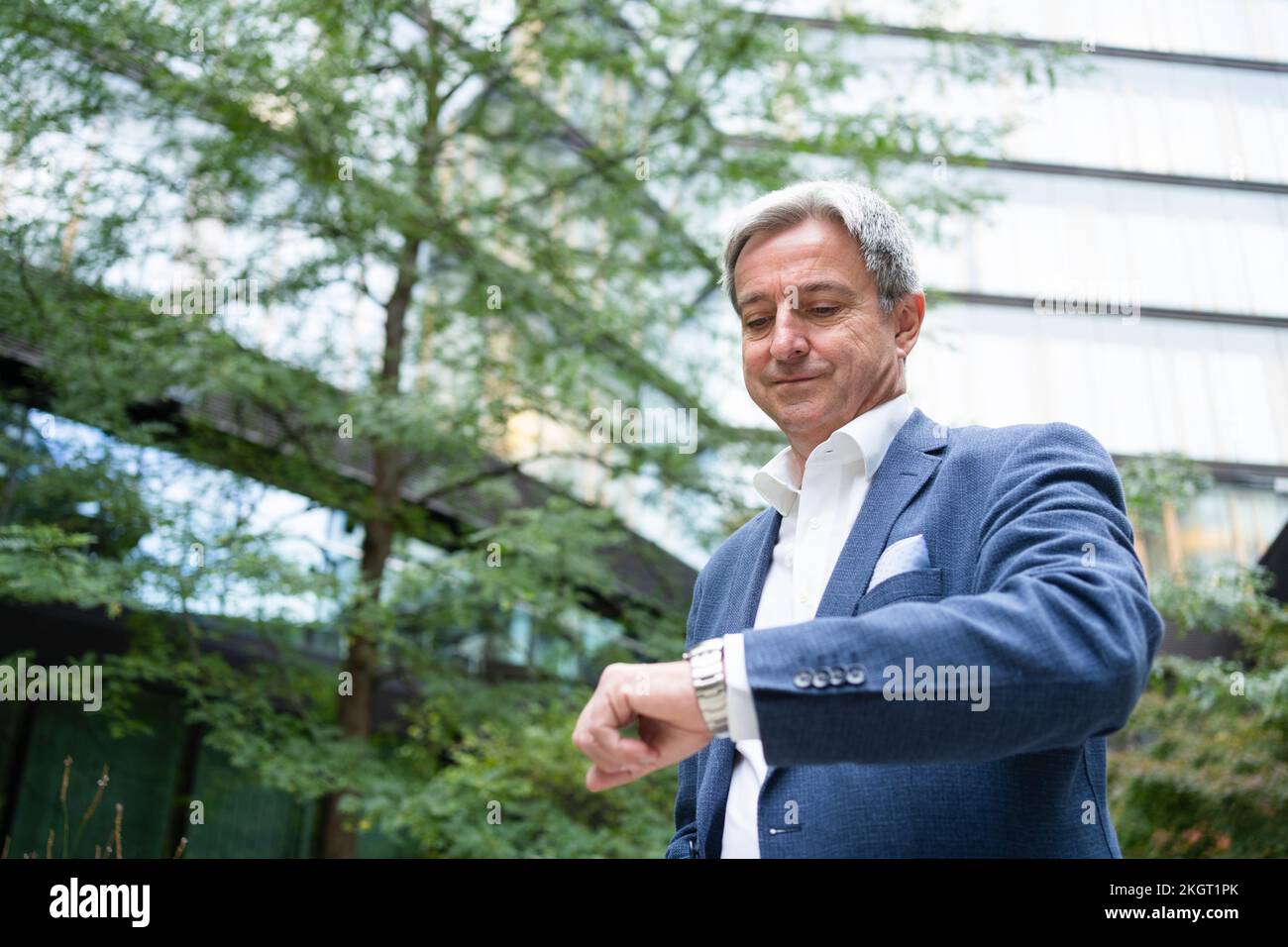 Mature businessman checking time on watch in office park Stock Photo ...