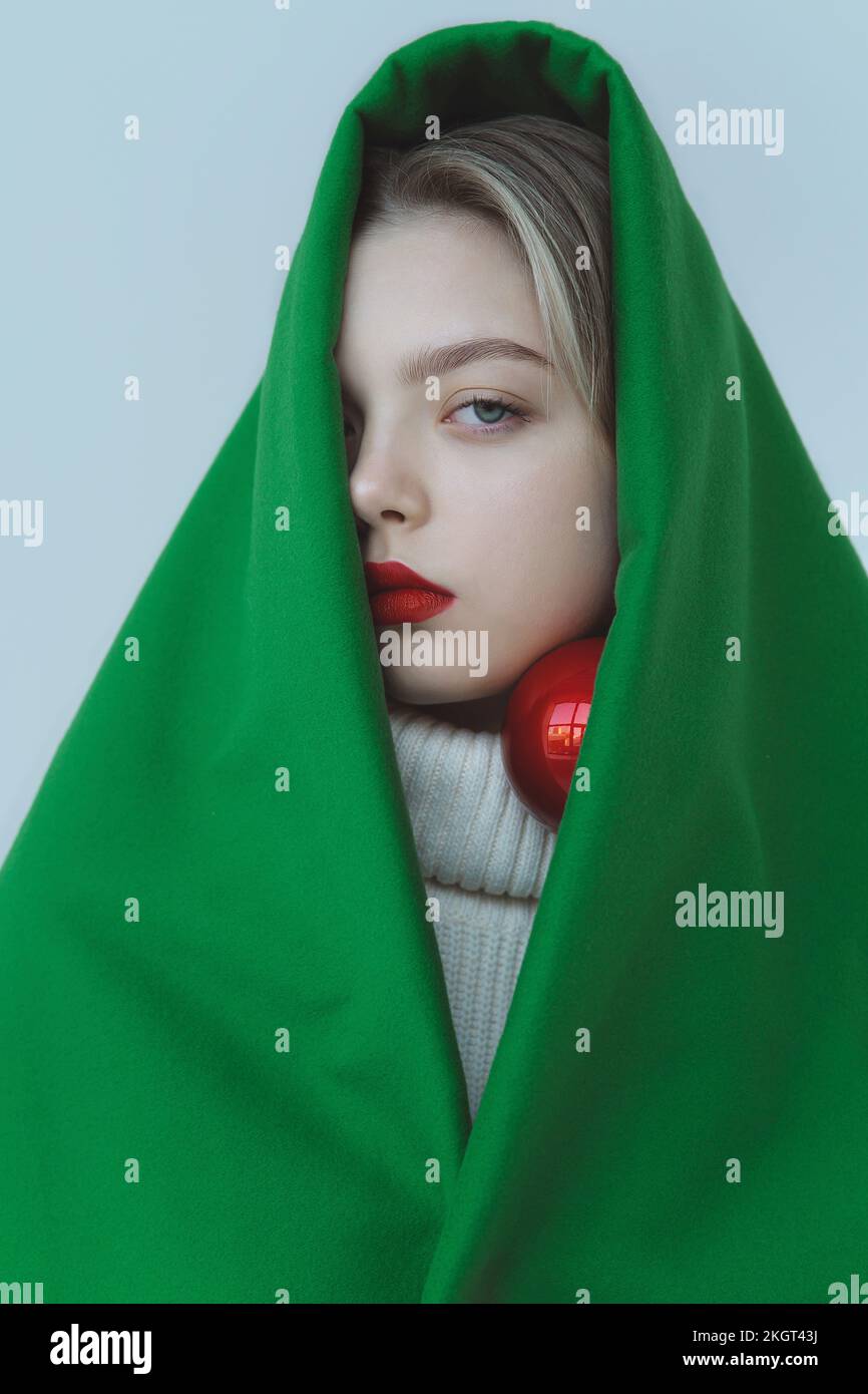 Teenage girl wrapped in green velvet cloth against white background