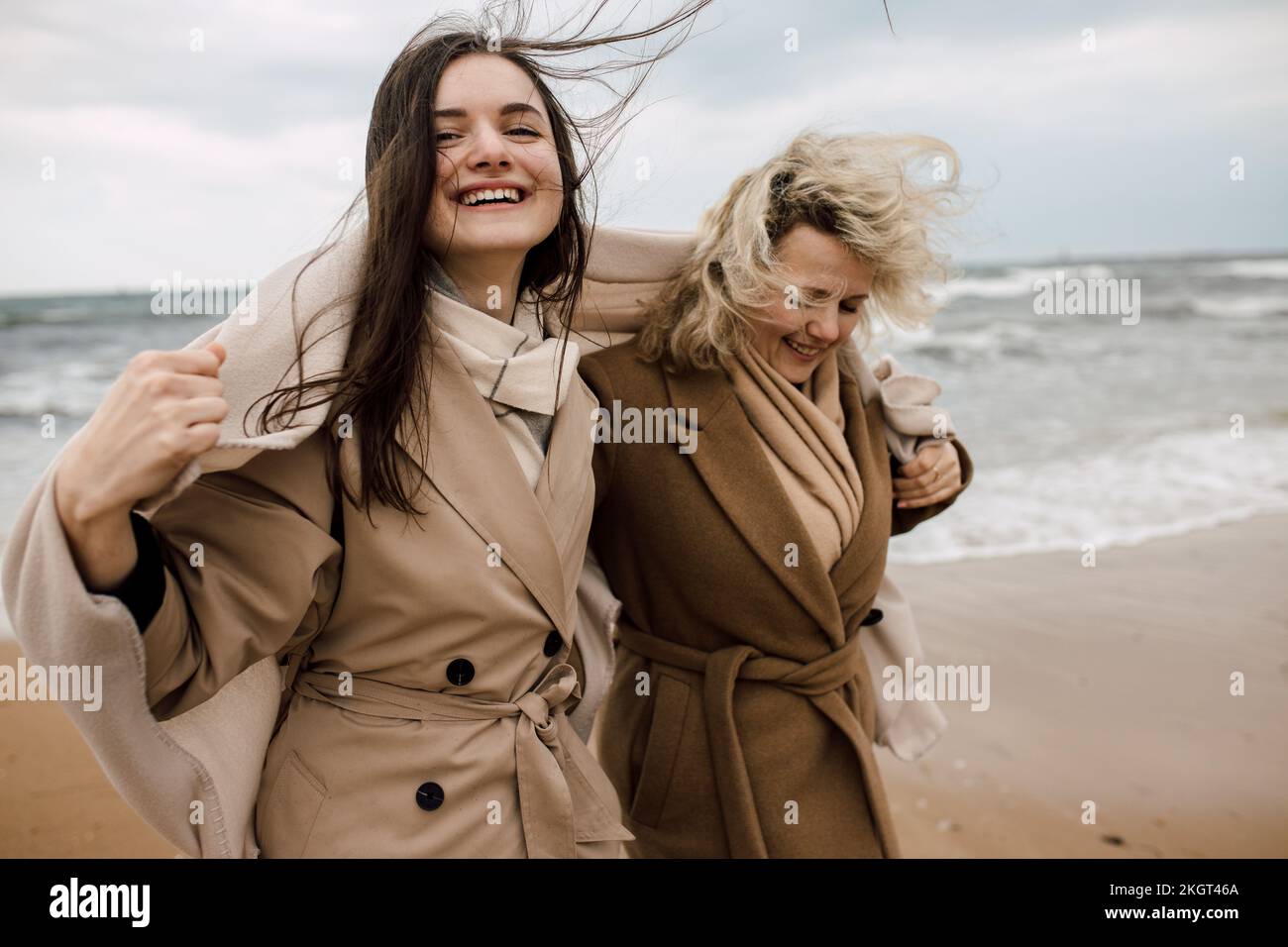 Mother and daughter wearing overcoats enjoying at beach Stock Photo