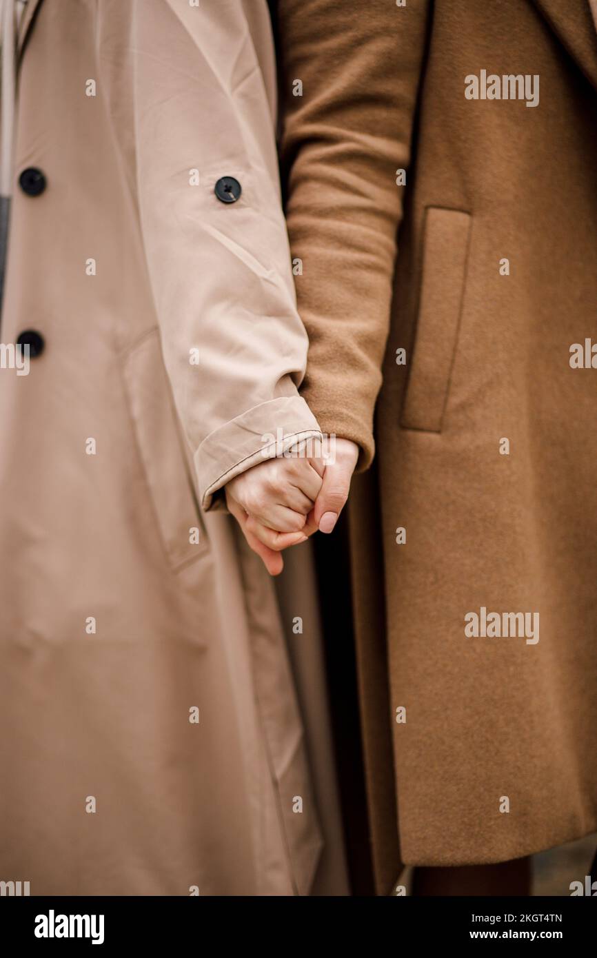 Women wearing overcoats holding hands Stock Photo Alamy