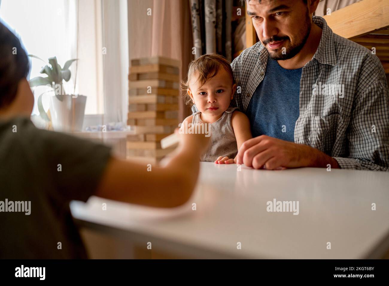 Father playing block removal game with sons at home Stock Photo Alamy