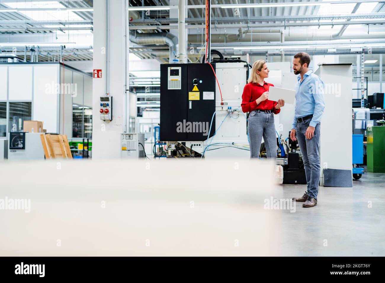 Colleagues talking to each other standing at factory Stock Photo