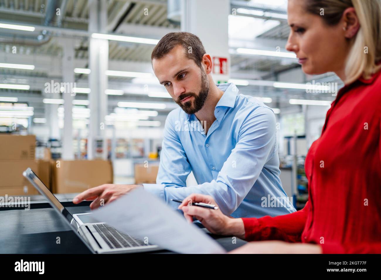 Businessman pointing at laptop with colleague at factory Stock Photo