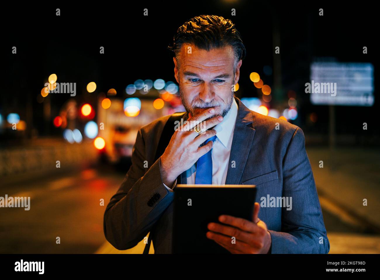 Thoughtful mature businessman standing with tablet PC at street Stock Photo
