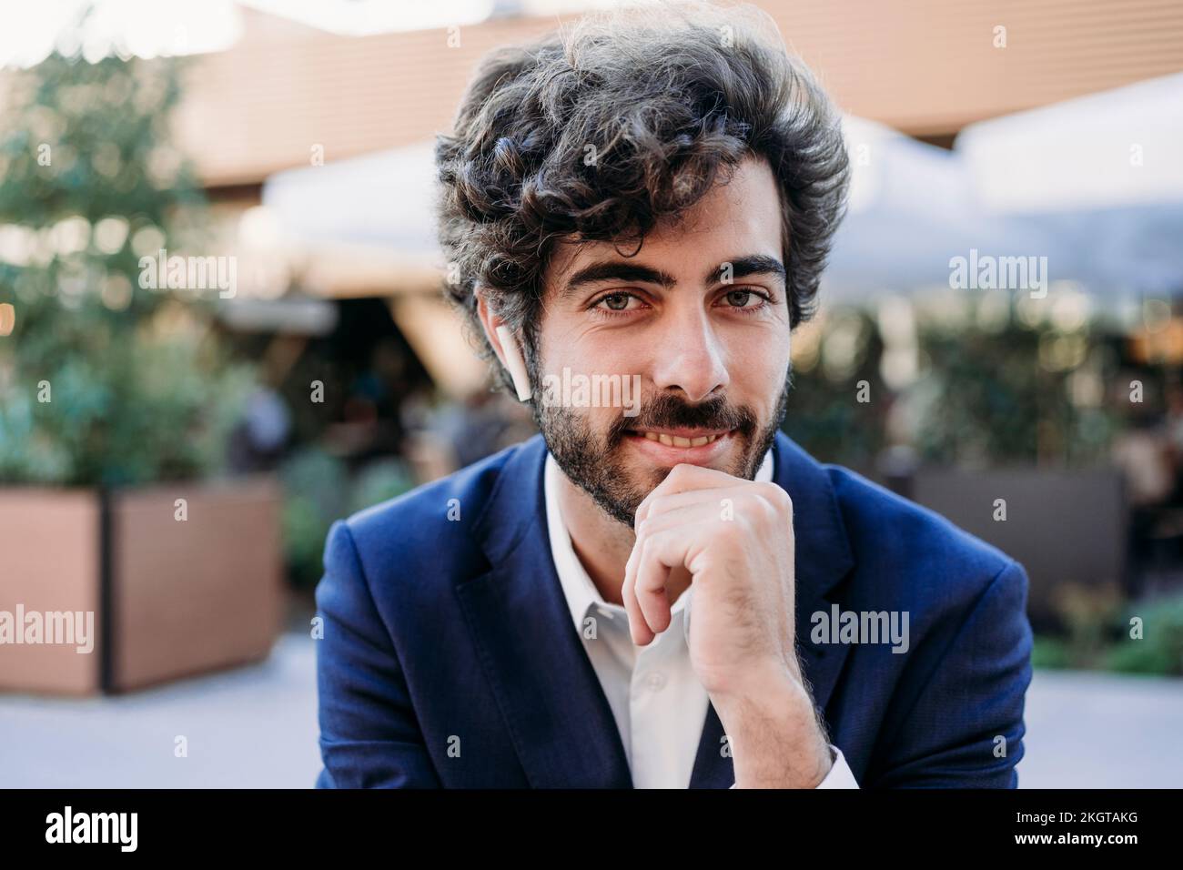 Businessman with hand on chin wearing in-ear headphones Stock Photo