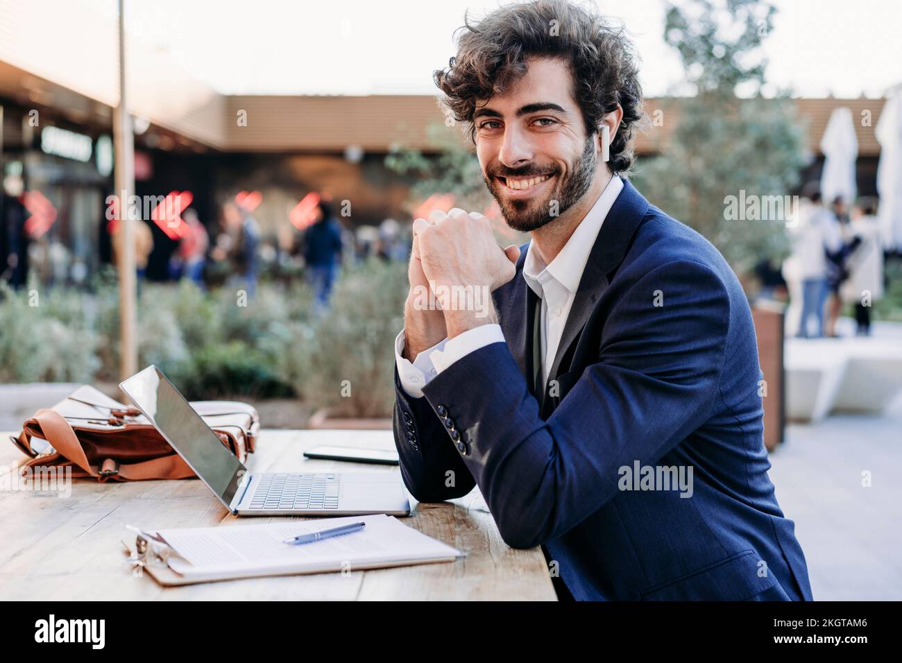 Smiling businessman leaning on elbows sitting at table Stock Photo