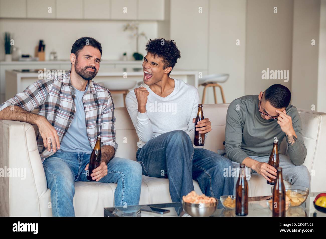 Gleeful young man gloating over his despondent buddies Stock Photo