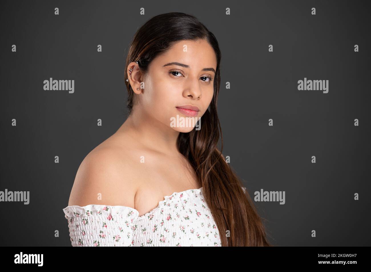 Portrait of latin girl with piercing in ear on dark studio background Stock Photo