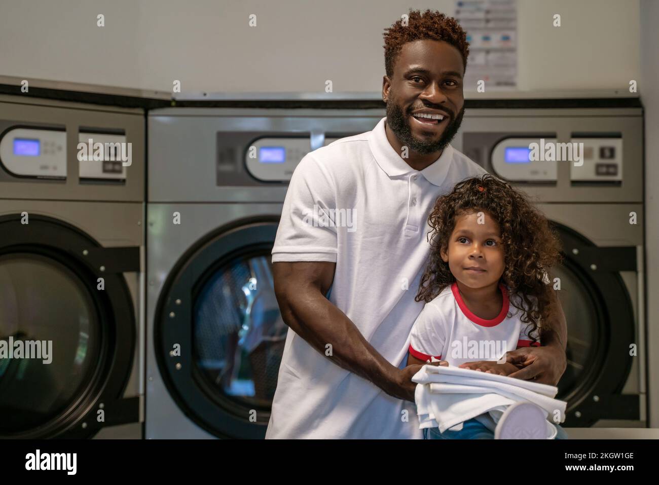 Joyous male and his daughter at the launderette Stock Photo