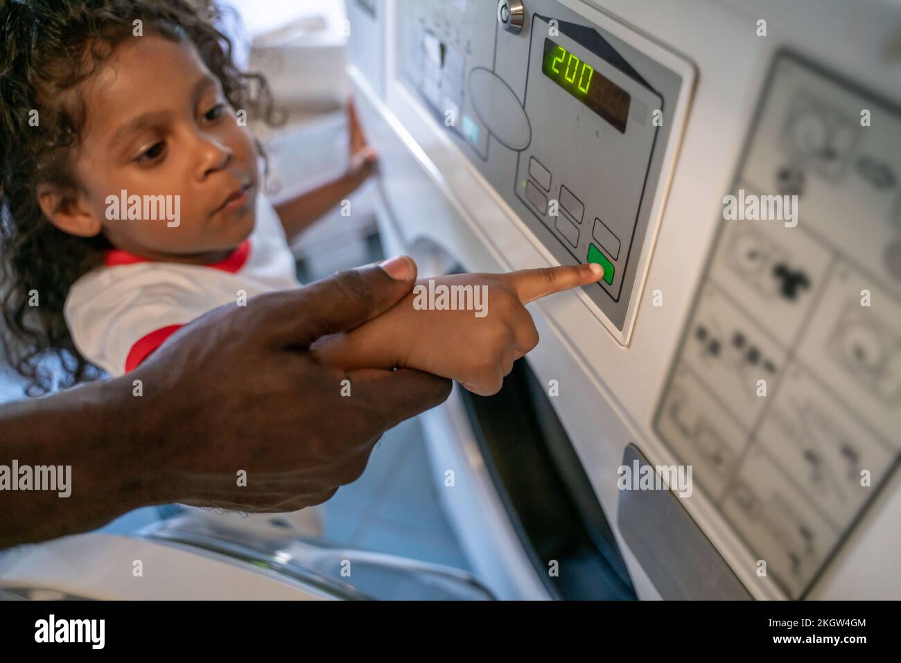 Serious child selecting the right settings on a washer Stock Photo