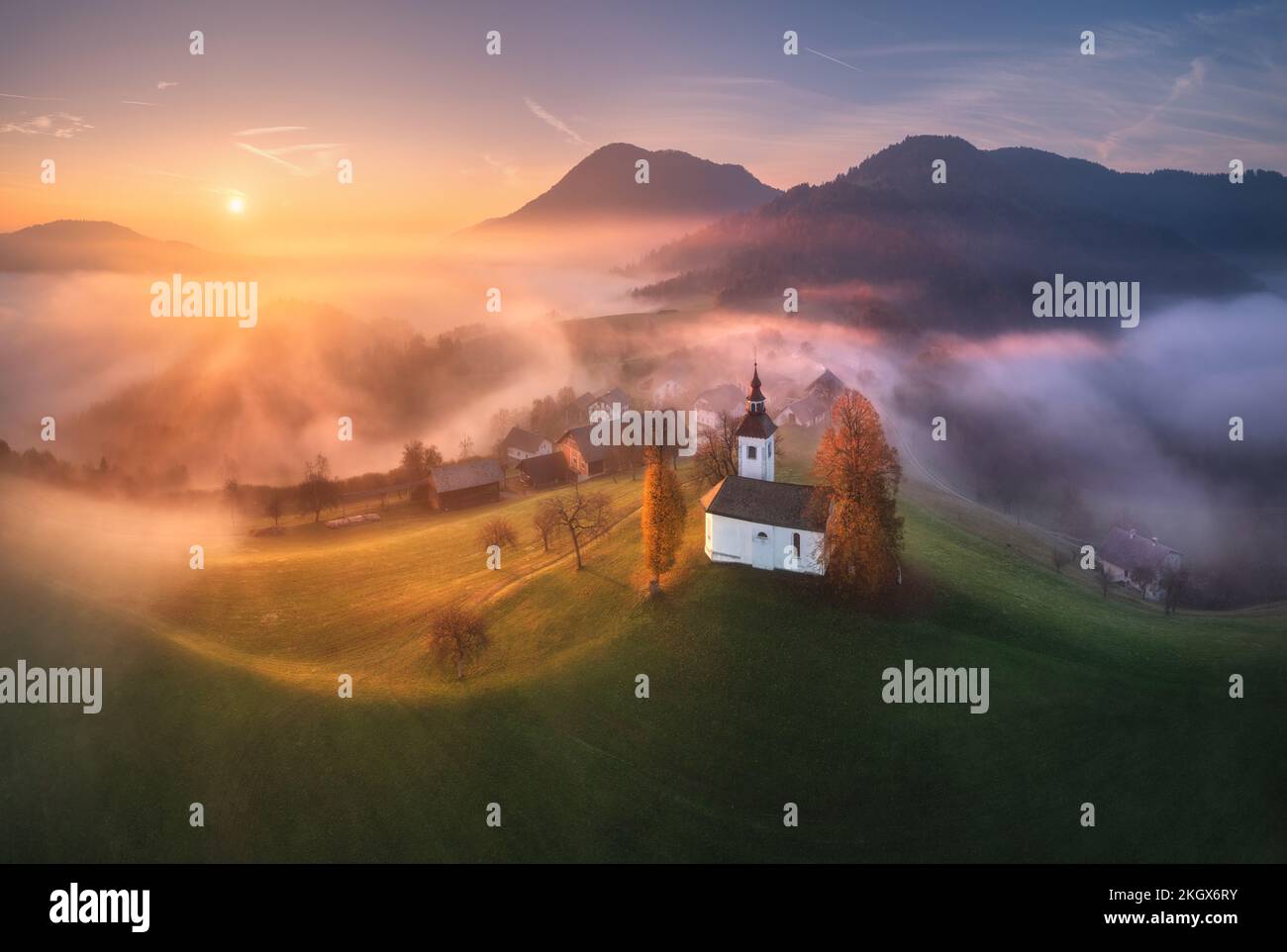 Aerial view of small church on the hill over pink low clouds Stock Photo