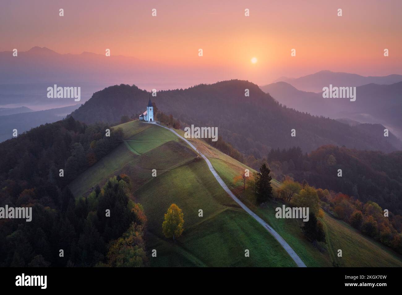 Aerial view of small church on the mountain over low clouds Stock Photo