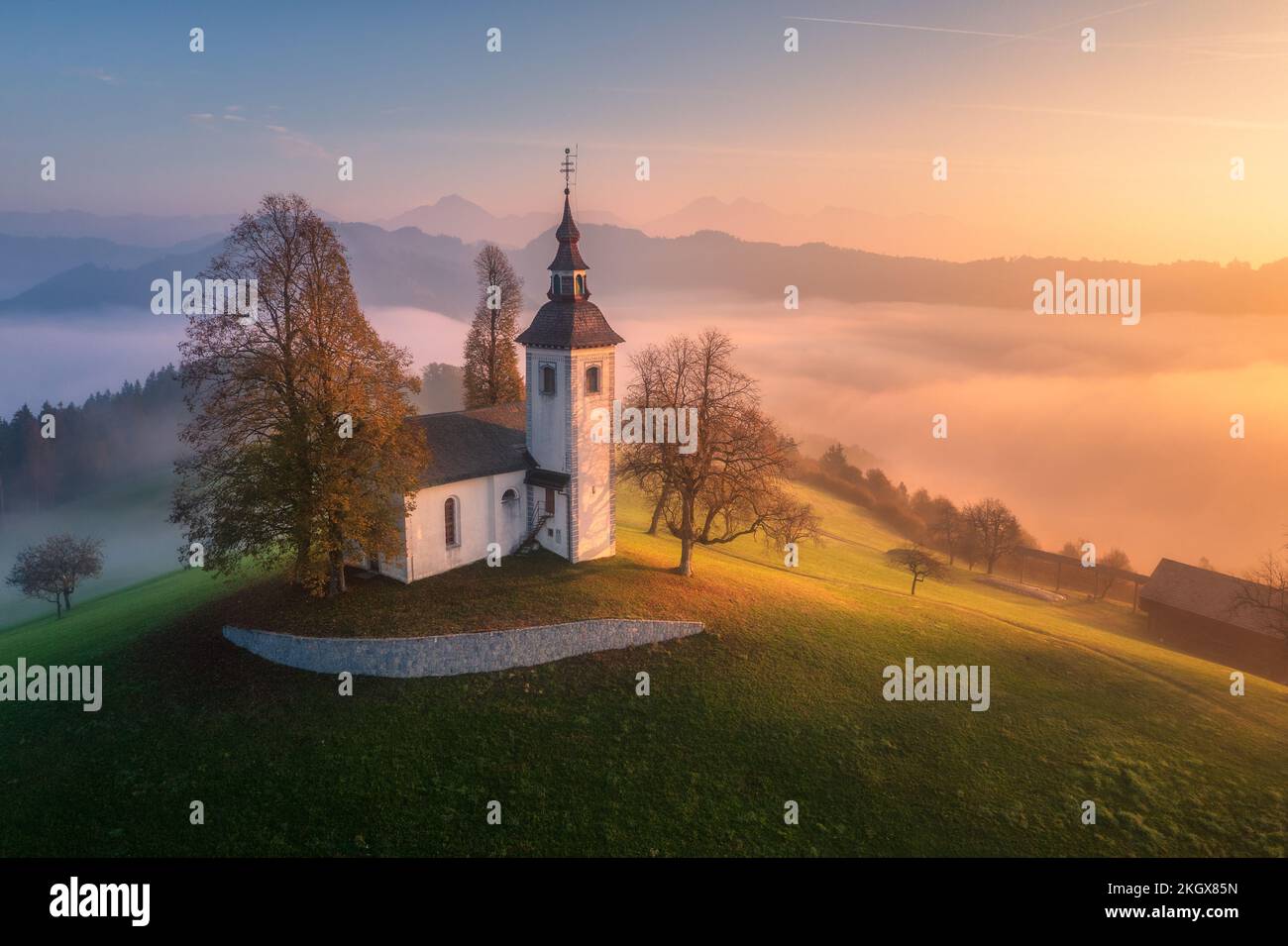 Aerial view of small church on the hill and orange low clouds Stock Photo