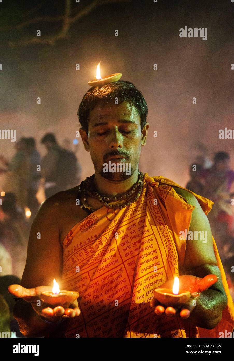 Bangladeshi Hindu devotees sit with candles and pray to God at the Shri