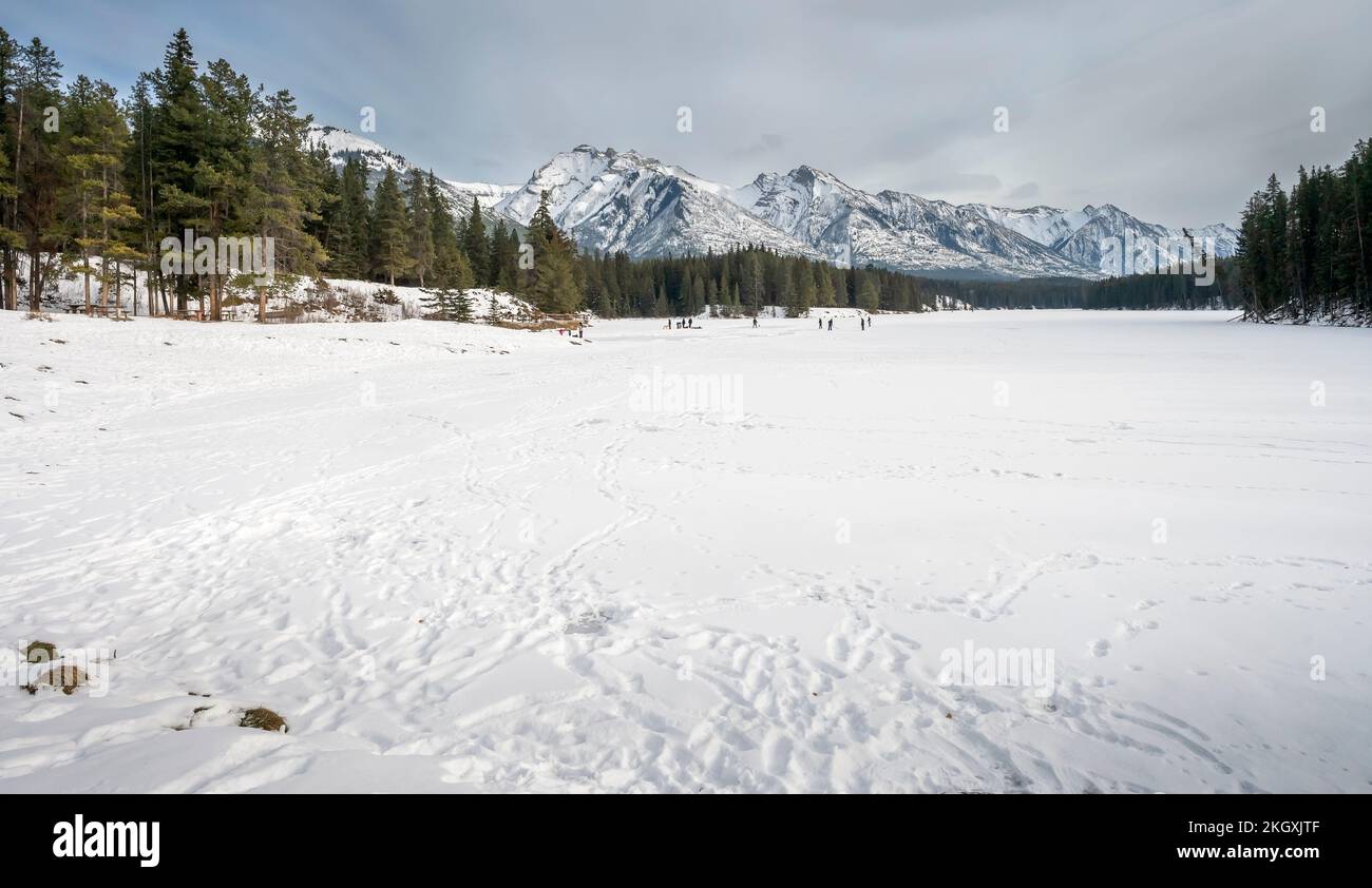 Unrecognizable people skate and play hockey on frozen Johnson Lake in Banff, National Park, Alberta, Canada Stock Photo