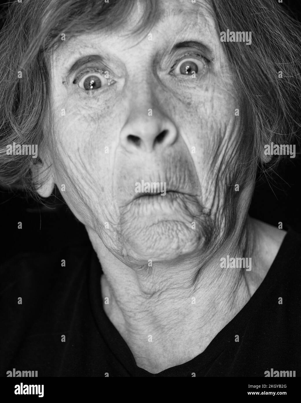 Portrait of senior caucasian woman making funny face on black background Stock Photo