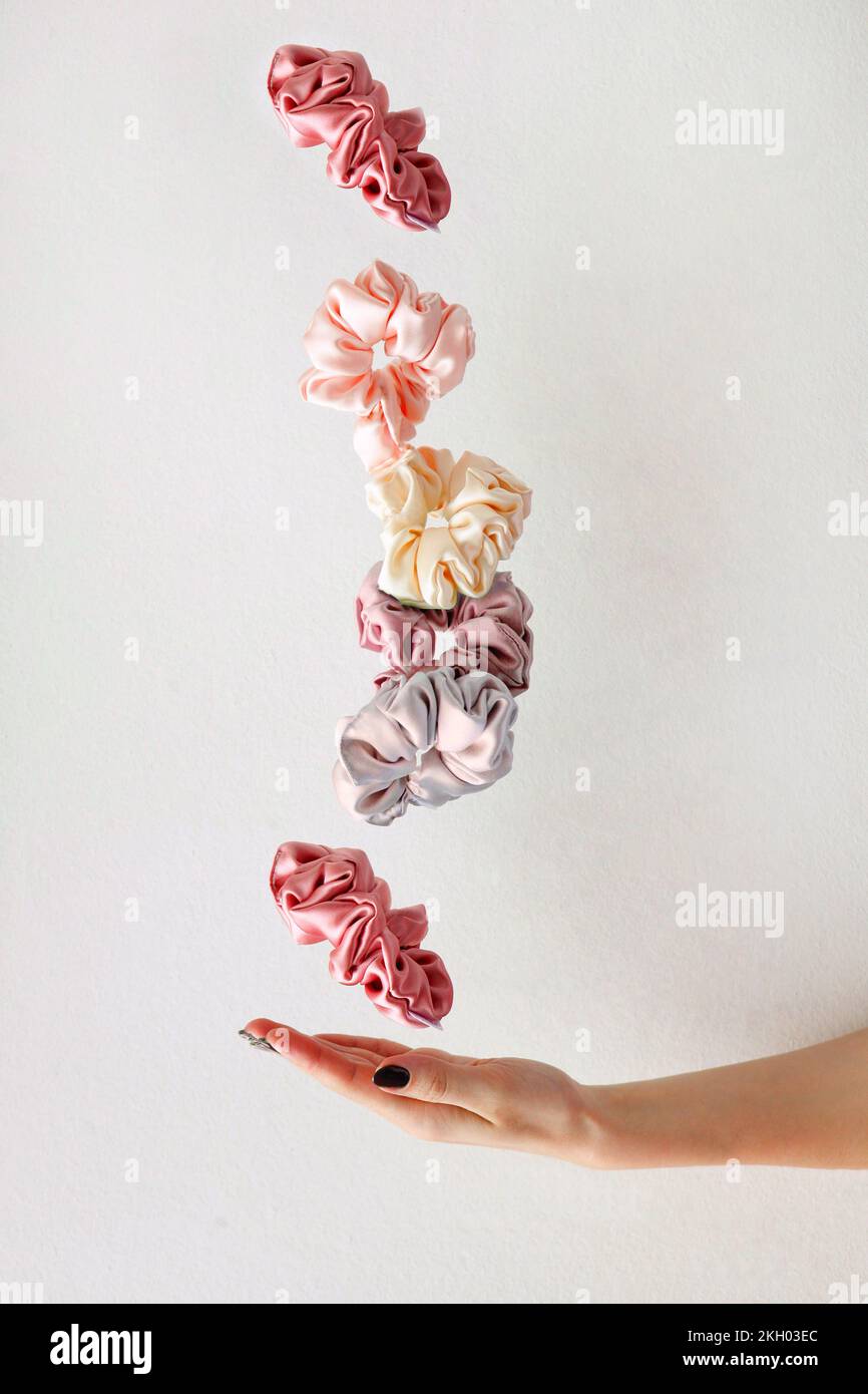 levitation of Colorful silk Scrunchies on woman hand isolated white. Hair tools and accessories. Stock Photo