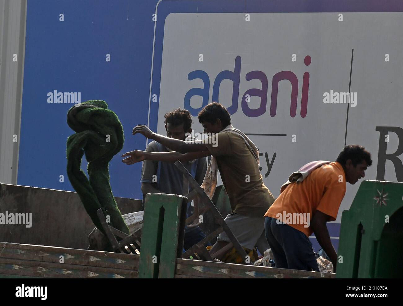 People are seen working on a truck next to the Adani logo on a poster in Mumbai. Adani group is a diversified multinational business conglomerate dealing in energy, infrastructure, transport logistic enhancing lives and empowering India through growth. Stock Photo