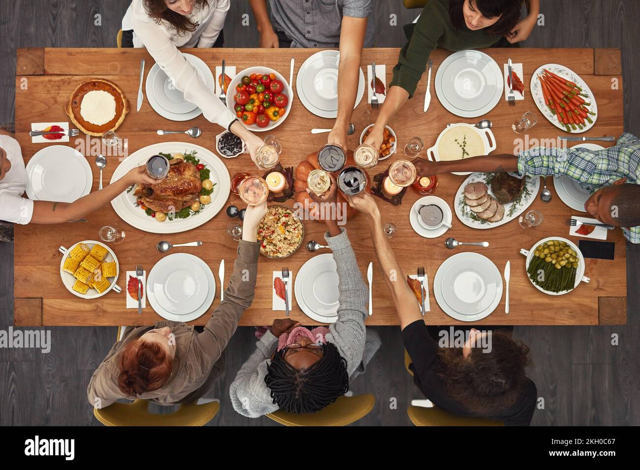 Food, top view and friends toast at a table in celebration of thanksgiving at a party or social event together. Cheers, support and happy people with Stock Photo