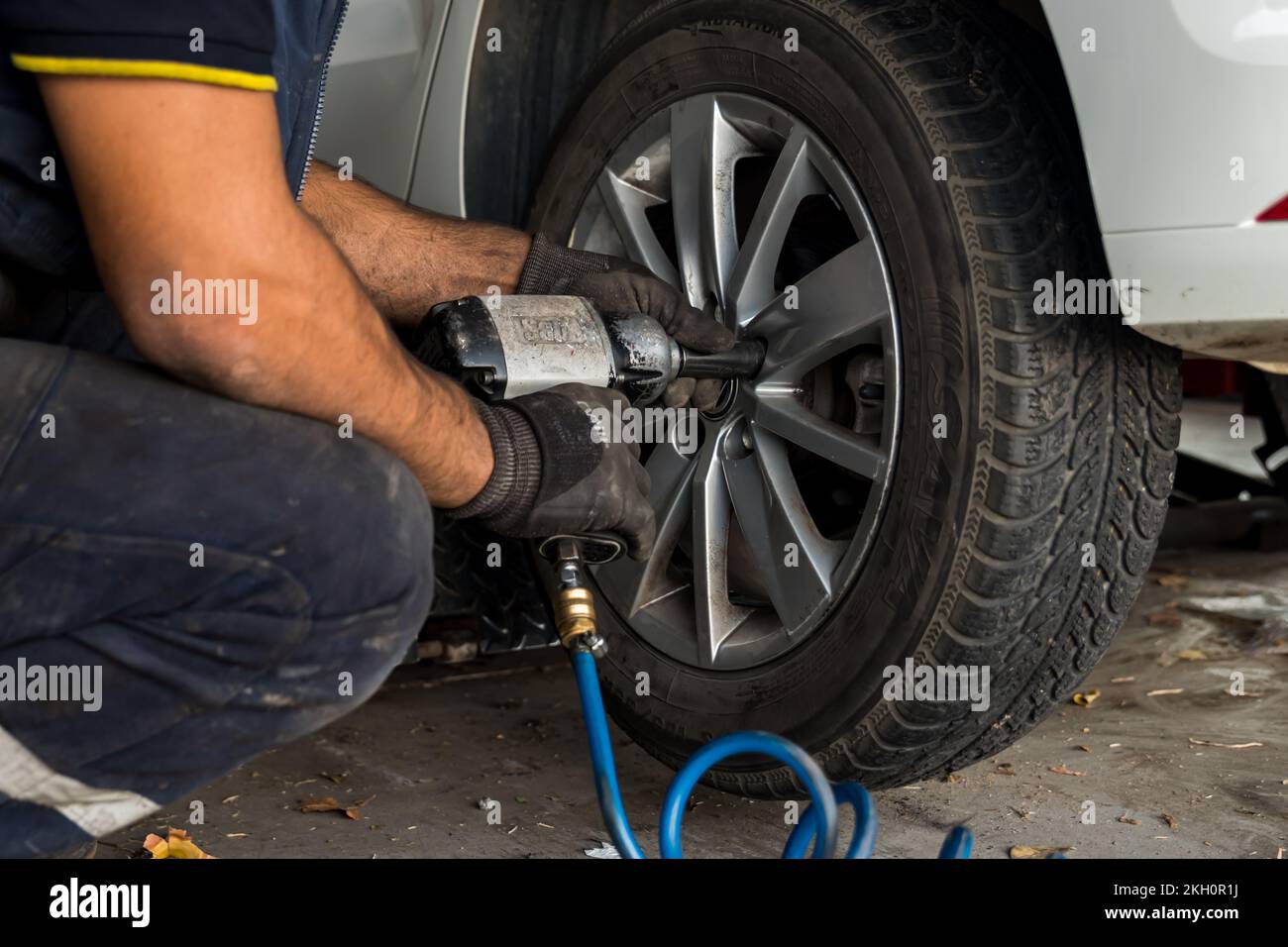 Auto Mechanic Man With Electric Screwdriver Changing Tire Outside Car Service Tire