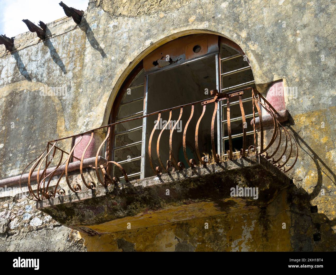 Lost Place in Eleousa. Detail view of an old rusty balcony. Village on ...