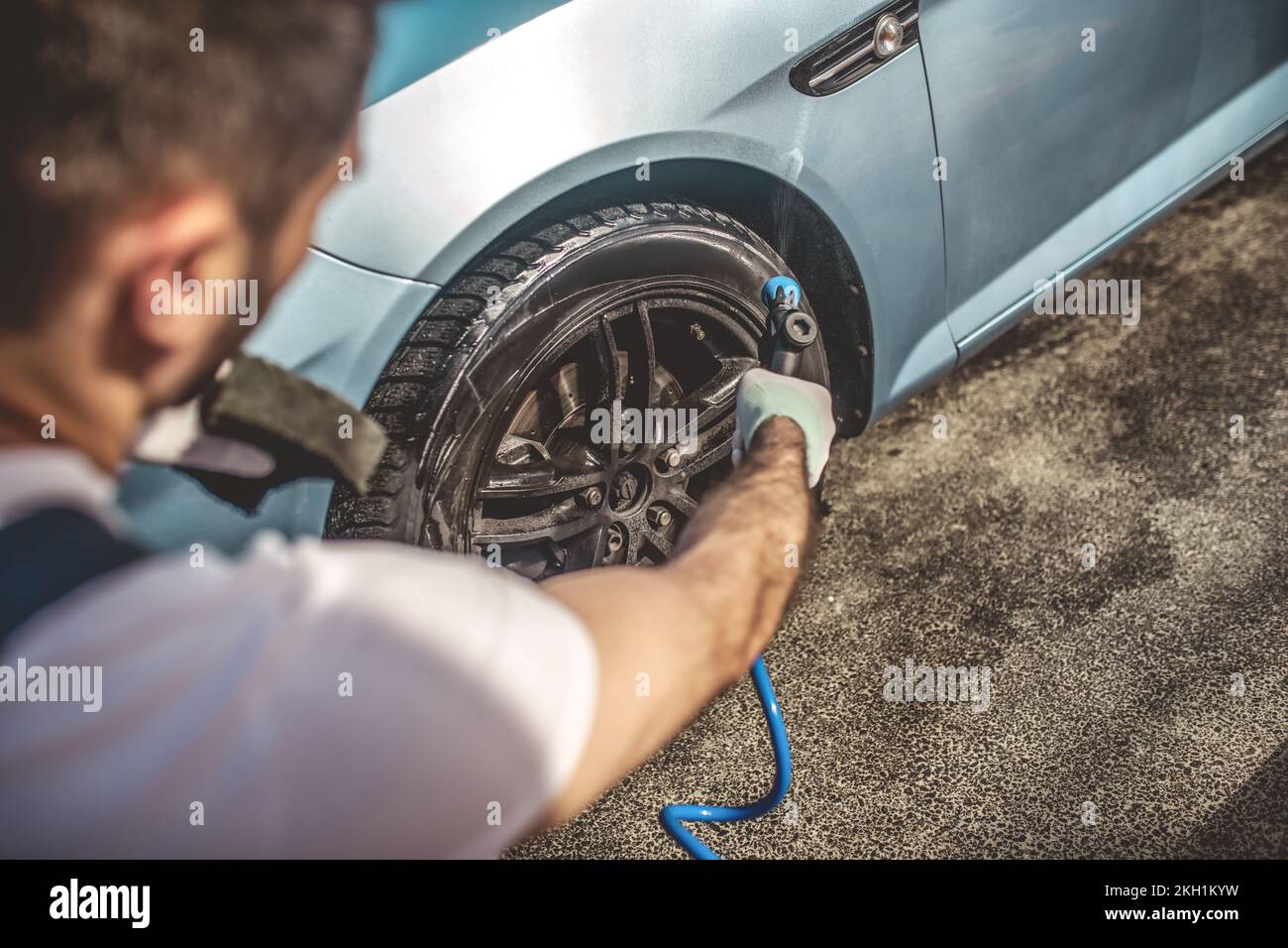 Service station worker power-washing the car wheel Stock Photo