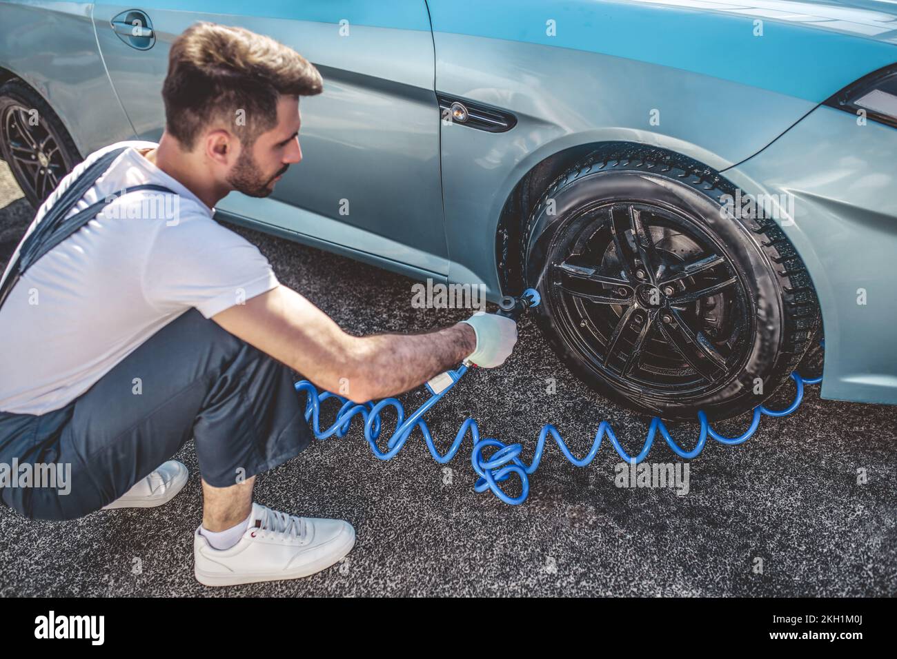 Automotive detailer power-washing a client vehicle wheel outdoors Stock Photo