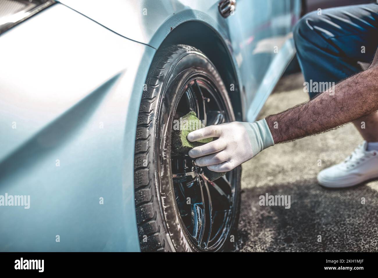 Professional service station worker cleaning an automobile wheel Stock Photo