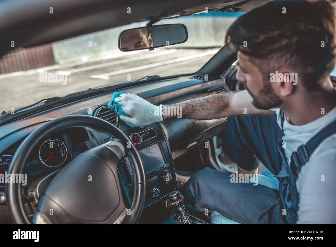 Professional auto service worker washing car interior surfaces Stock Photo