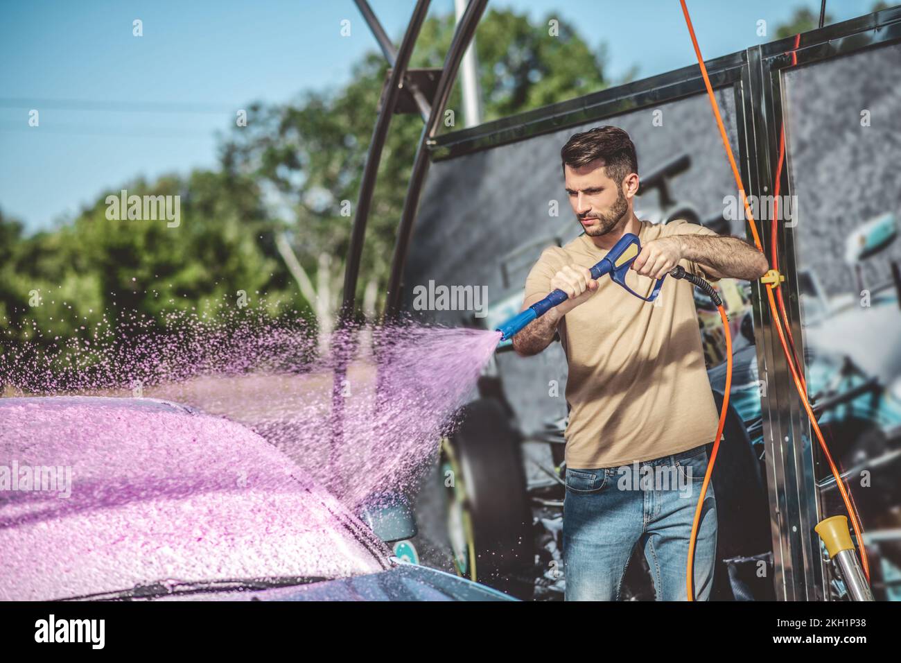 Service station worker washing a customer auto using professional equipment Stock Photo