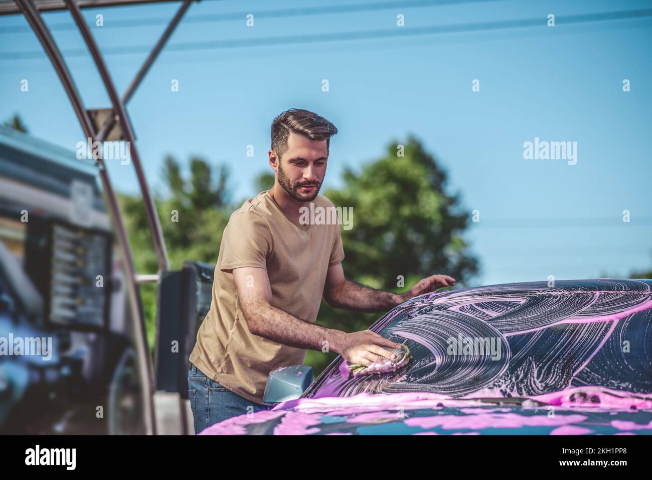 Service station worker cleaning an automobile windshield outdoors Stock Photo