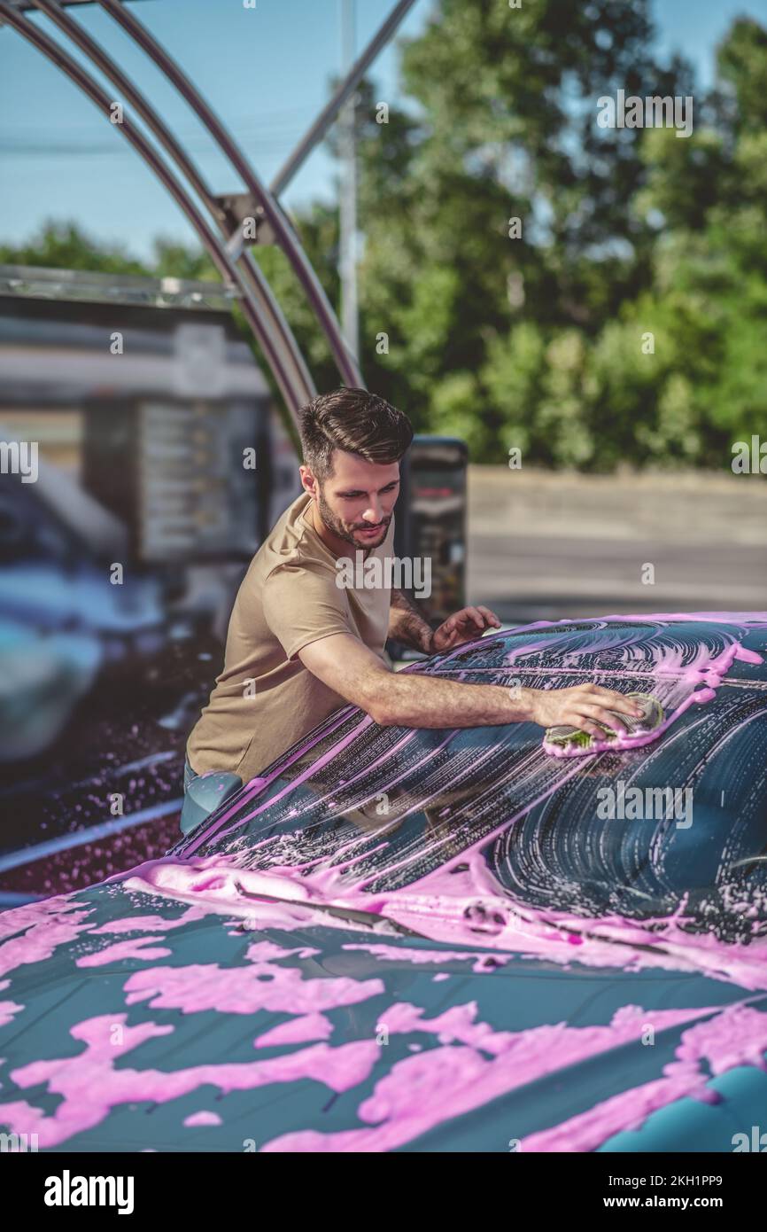 Automotive detailer washing the motor vehicle windscreen outdoors Stock