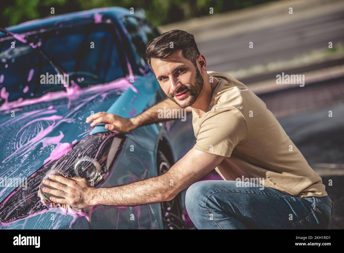 Pleased automobile service worker cleaning a vehicle headlight Stock Photo