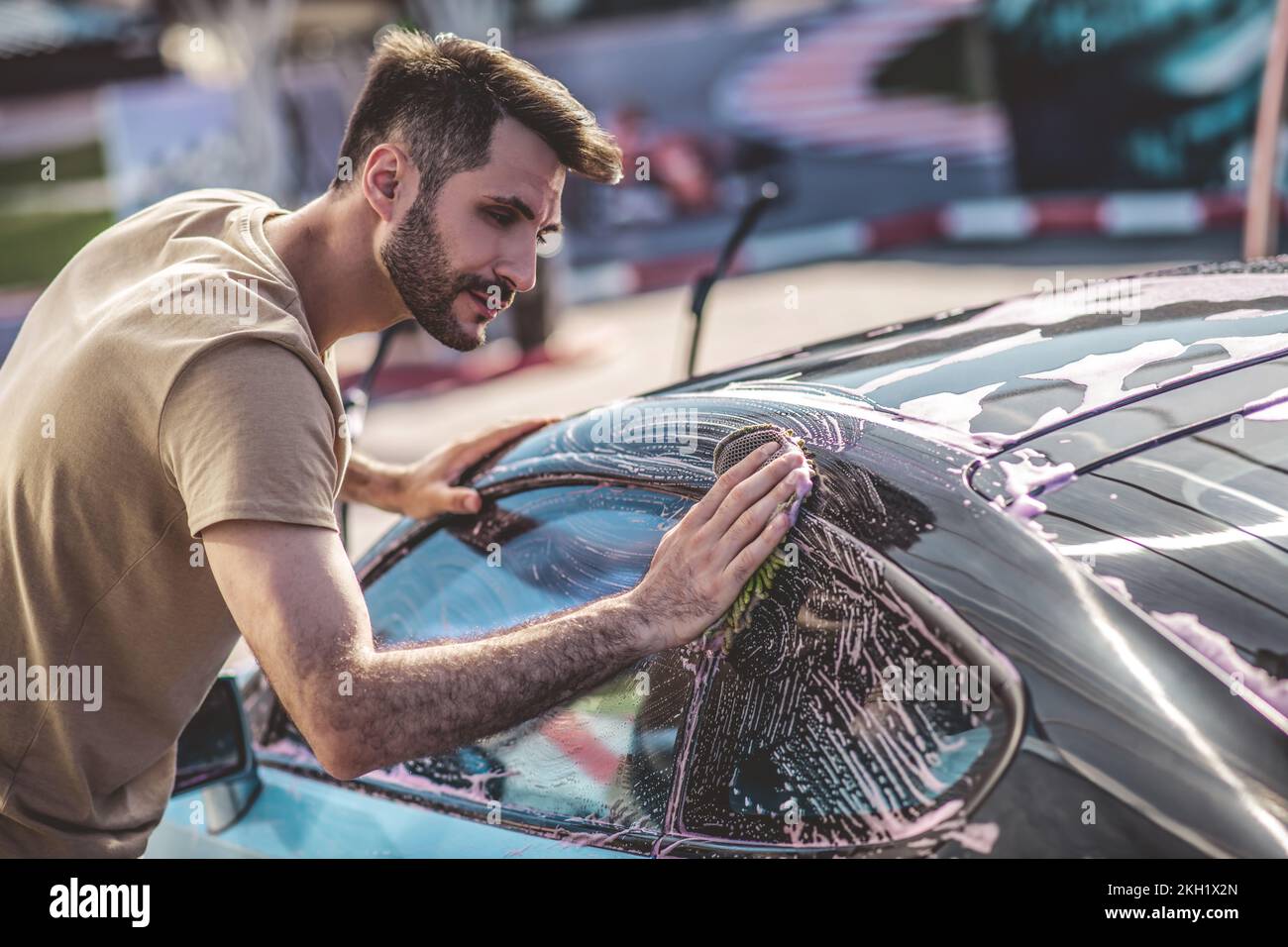 Service station worker washing the exterior of a passenger car Stock Photo