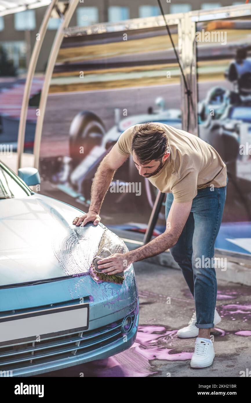 Service station worker cleaning the car headlight Stock Photo