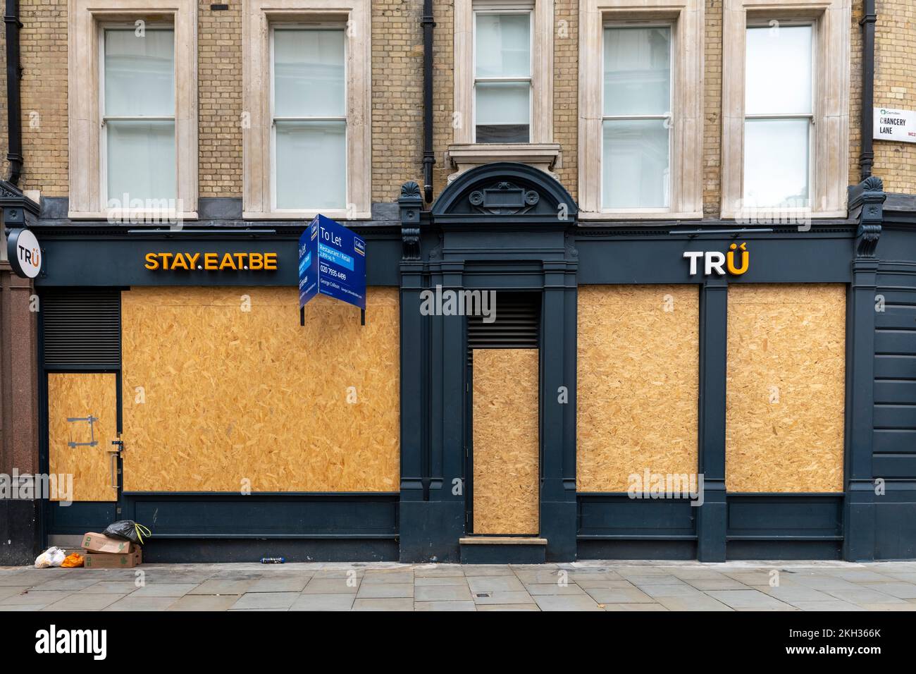 People walking past a closed down and boarded up restaurant / cafe, High Holborn, London, UK.  22 Oct 2022 Stock Photo