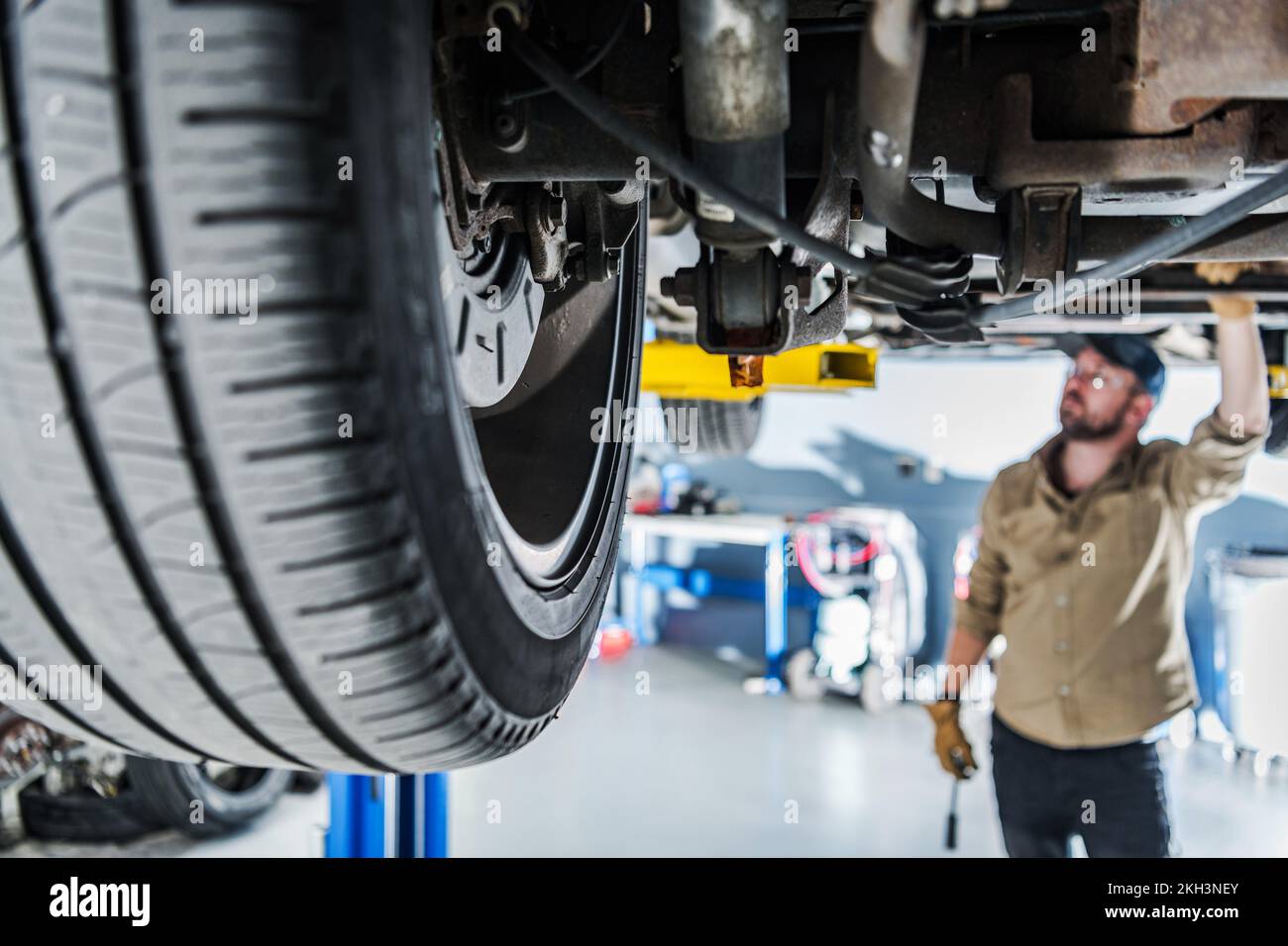 Closeup of Suspension and Wheel of Vehicle Lifted on Car Lift at