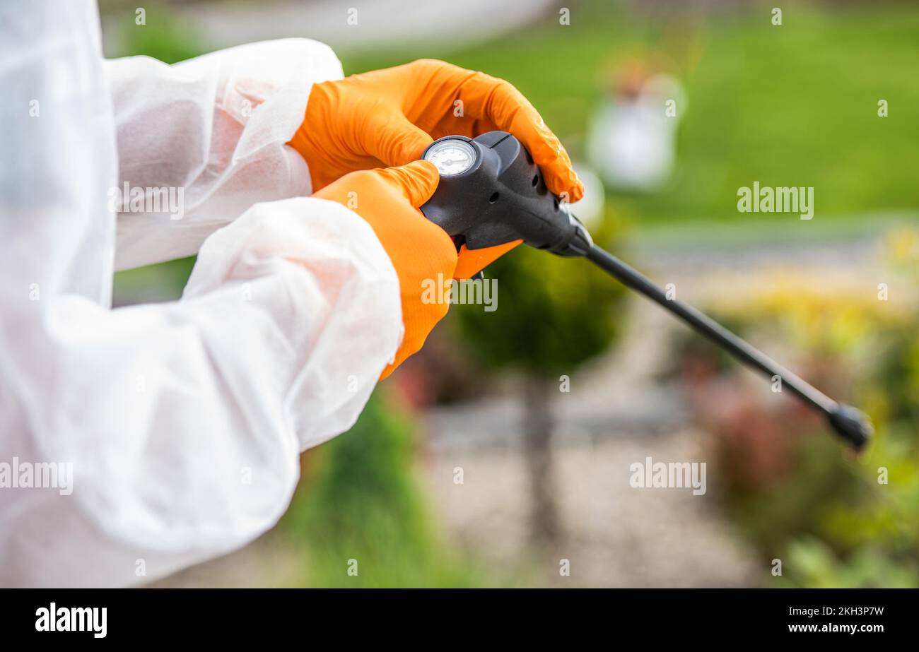 Professional Gardener in Safety Outfit Calibrating Pesticide Sprayer