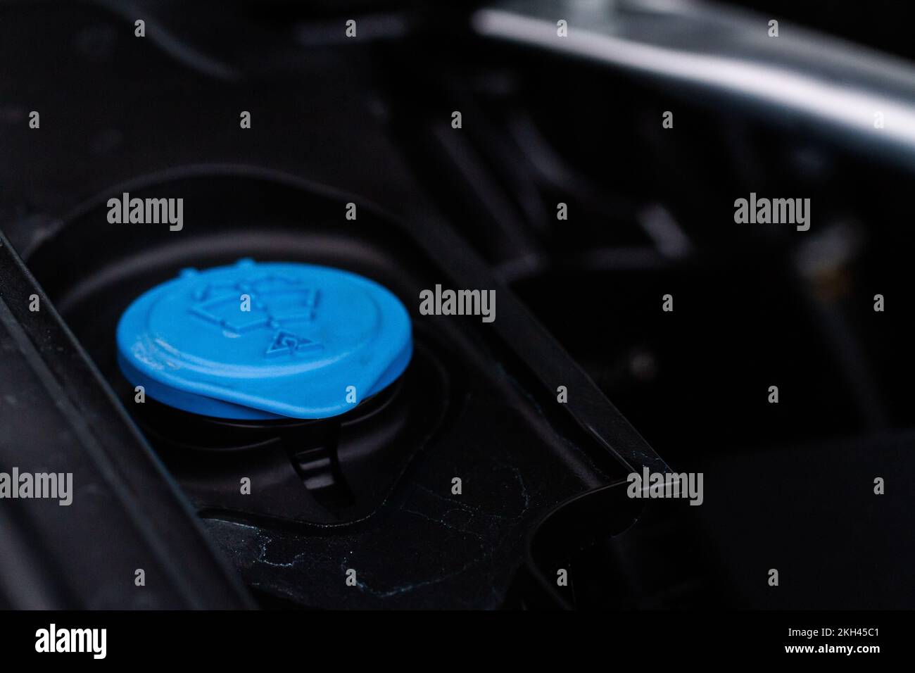Closeup blue windshield washer fluid reservoir cap in engine room
