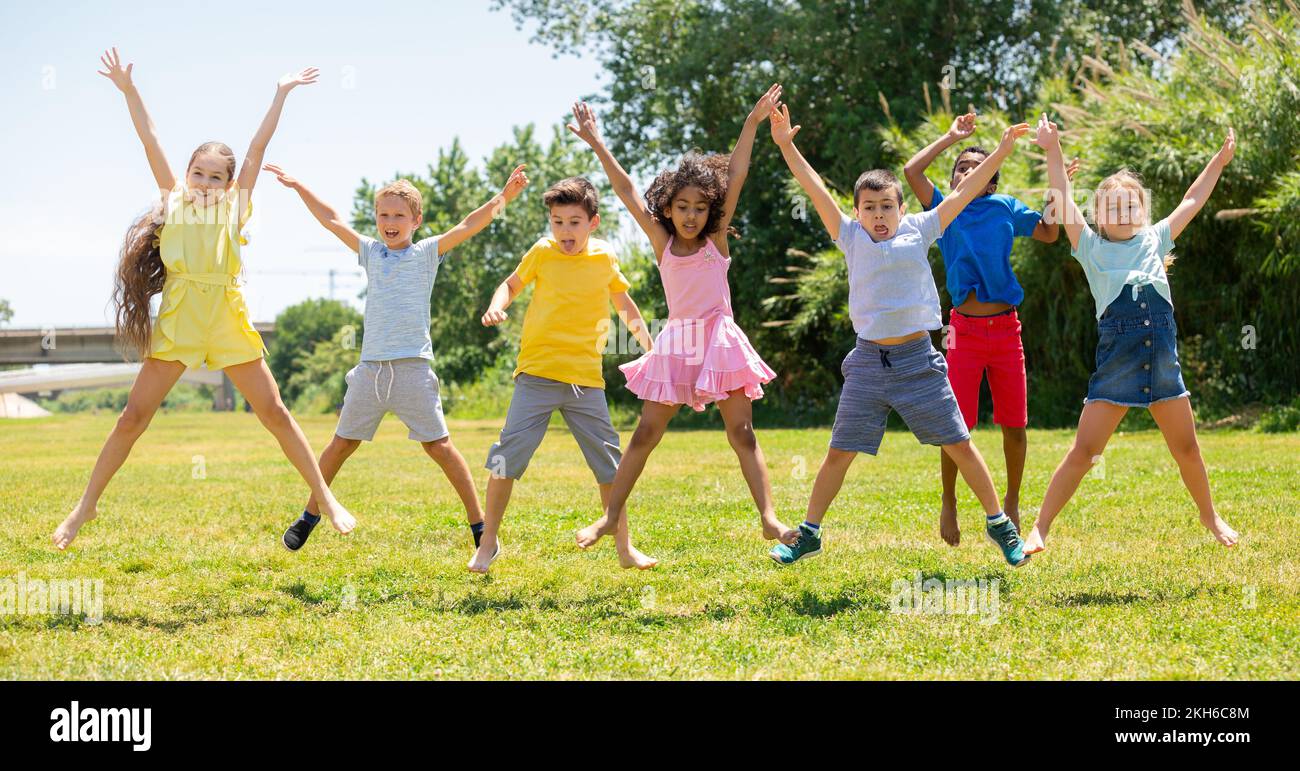 Schoolchildren jumping and smiling together in park Stock Photo - Alamy
