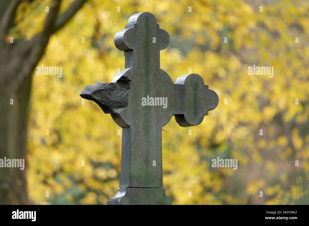 damaged stone cross in an autumnal cemetery Stock Photo