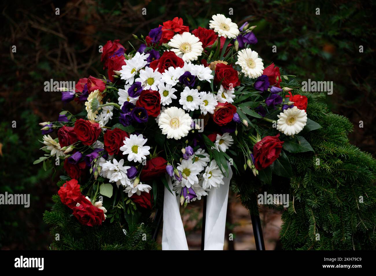 funeral wreath in a cemetery with colorful flowers and bow on a metal stand Stock Photo