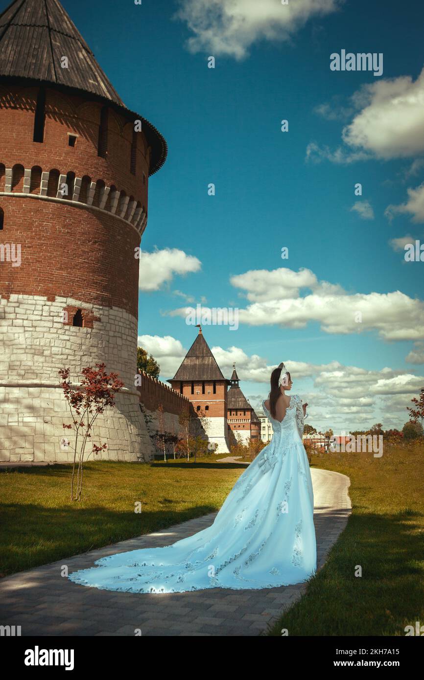 a girl in a long wedding dress and a kokoshnik near an old wall. russian tsaritsa Stock Photo