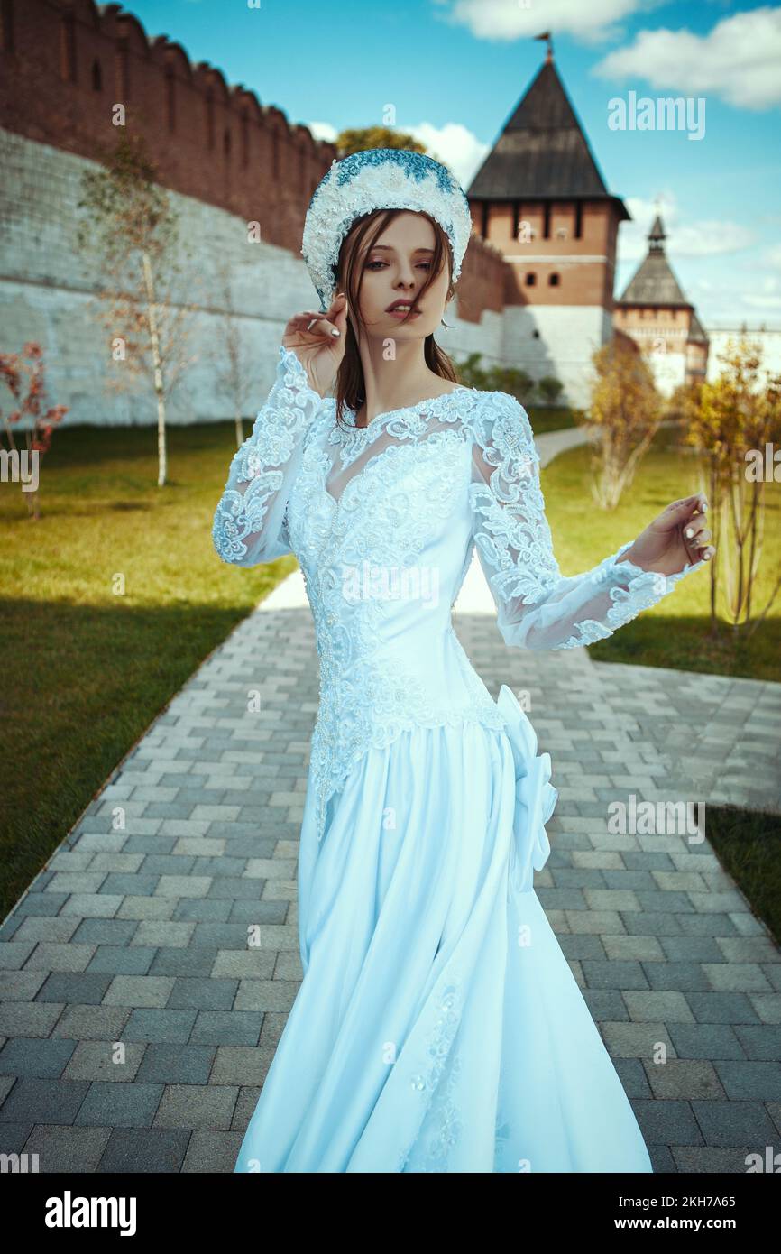 a girl in a long wedding dress and a kokoshnik near an old wall. russian tsaritsa Stock Photo