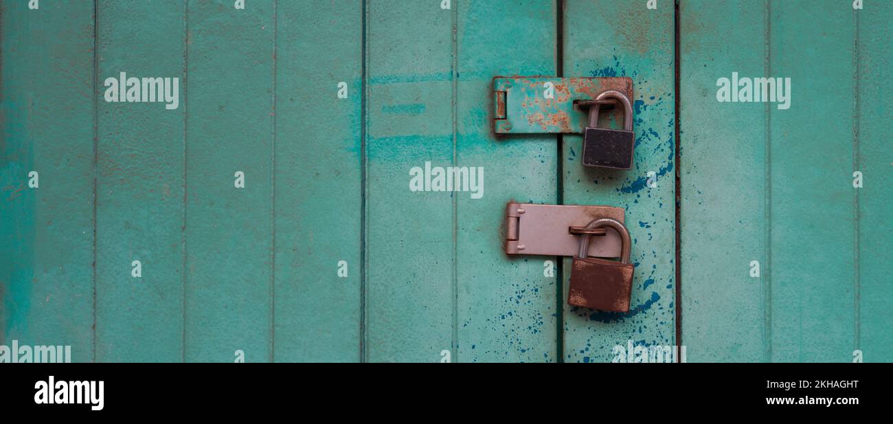Two padlocks on turquoise vintage wooden door Stock Photo