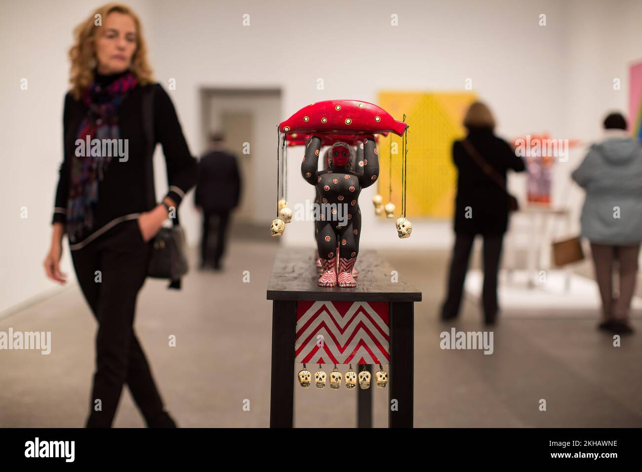 A woman observes a sculpture titled "Las cargadoras de platanos rojos