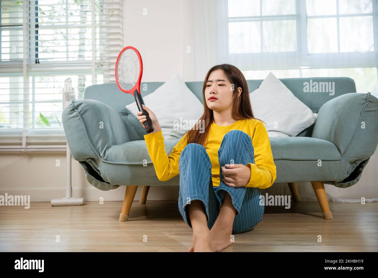 Woman killing mosquitoes hand holding fly swatter like weapon Stock Photo