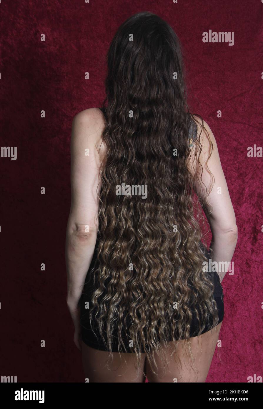 Woman With Natural Long Wavy Hair on Red Velvet Background Stock Photo