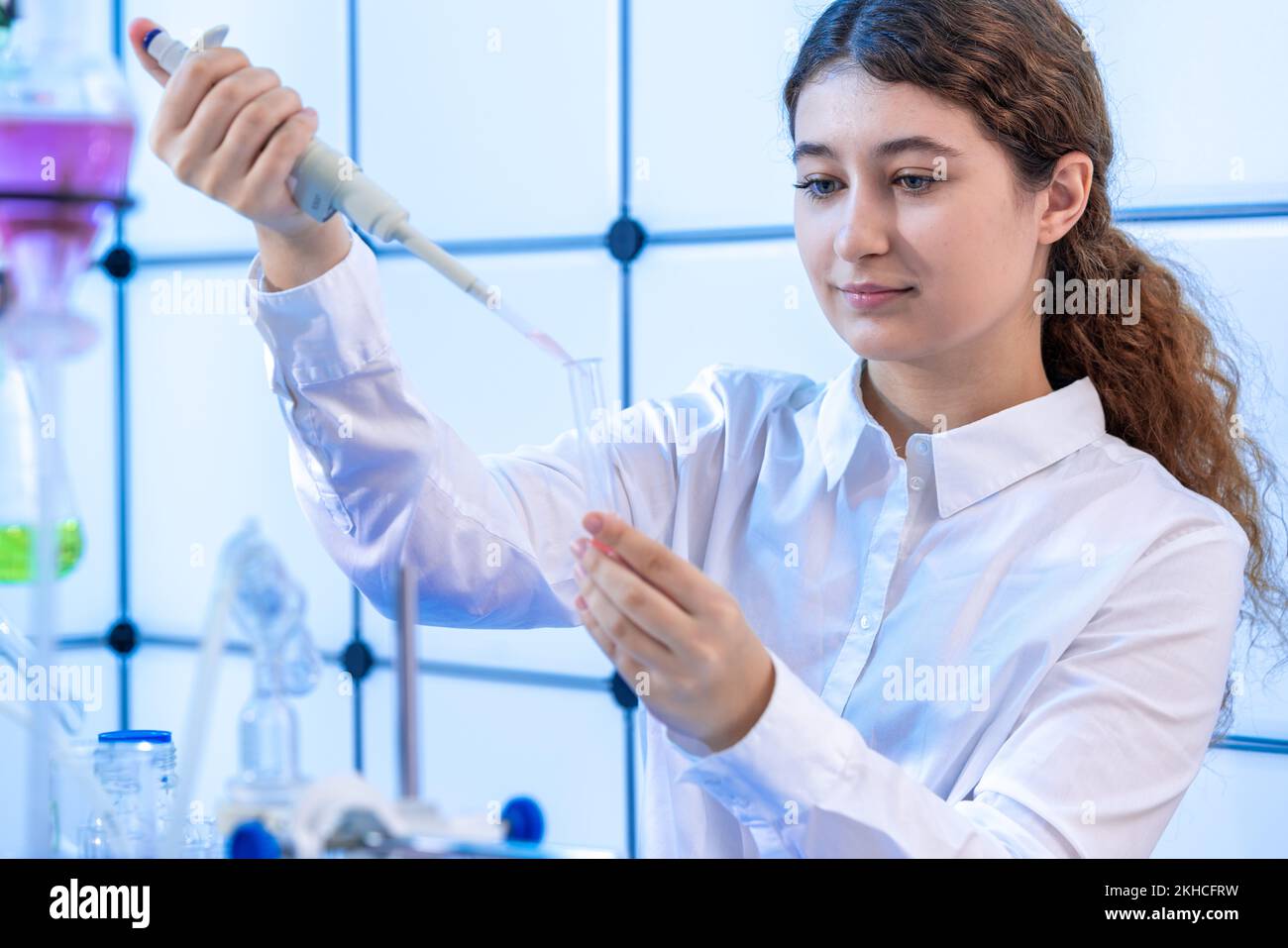 young woman filling a chemical test tube with a pipette in a chemical
