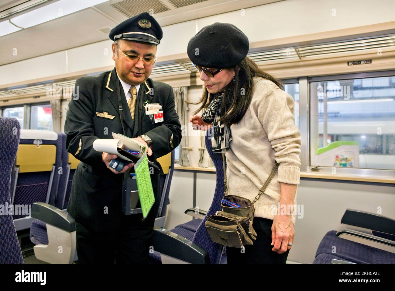 A train conductor helps a passenger in Tokyo, Japan Stock Photo